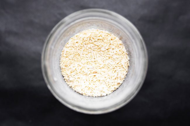 Top view of dried white onion spice in jar on dark background